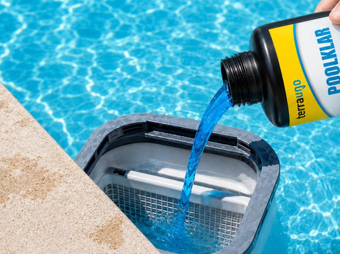 Eine Hand gießt blauen Poolreiniger aus einer Flasche mit der Aufschrift „POOLKLAR“ in den Korb eines Poolskimmers, der neben dem klaren, blauen Schwimmbadwasser steht.