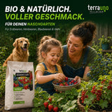 Eine Frau und ein Mädchen pflücken Beeren in einem Garten, während ihr Hund hinter ihnen läuft. Im Vordergrund ist „TerraUno Beerenstark – Bio-Beerendünger“ zu sehen, der auf natürliche Gartenpflege und zusätzlichen Kaliumgehalt für gesunde Beerenpflanzen setzt.