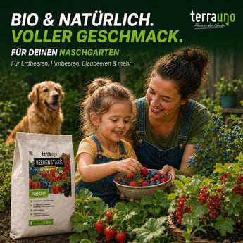 Eine Frau und ein Mädchen pflücken Beeren in einem Garten, während ihr Hund hinter ihnen läuft. Im Vordergrund ist „TerraUno Beerenstark – Bio-Beerendünger“ zu sehen, der auf natürliche Gartenpflege und zusätzlichen Kaliumgehalt für gesunde Beerenpflanzen setzt.