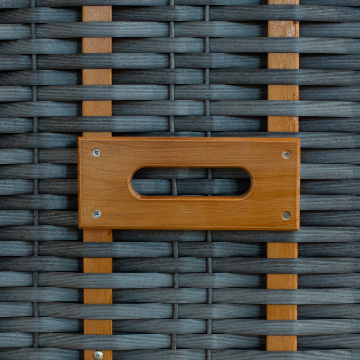 Nahaufnahme einer grauen, geflochtenen Oberfläche mit vertikalen Holzlatten und einem rechteckigen Holzgriff, der in der Mitte eine ovale Aussparung aufweist und mit vier Schrauben befestigt ist.