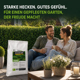 Ein lächelndes Paar entspannt sich auf Gartenmöbeln mit Tassen neben einem großen weißen Sack „TerraUno Heckenstark – Hecken-, Strauch-  Koniferendünger“. Der Text darüber hebt den biologischen, hochwertigen Dünger für kräftige Hecken und einen schönen Garten hervor.