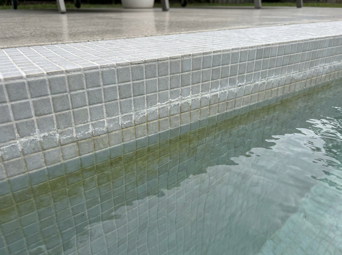 Kalkrand und Algenfilm an der Wasserlinie eines Pools ohne Wintermittel