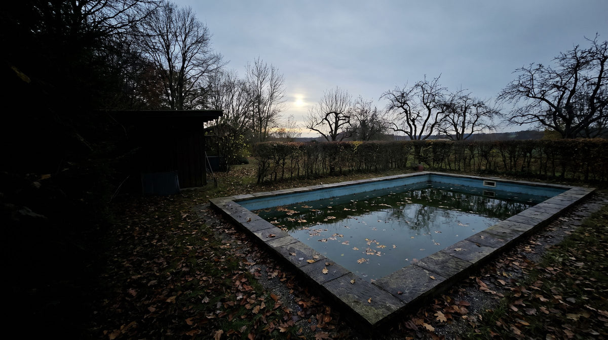 Privater Pool im Spätherbst, Wasser im Becken, Laub auf der Oberfläche